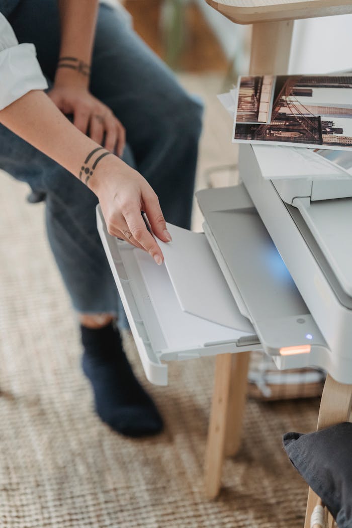 about-us A person handling a printer in a home office setting, focusing on placing paper.